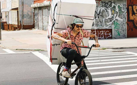 man hauling refrigerator on bicycle on city streets