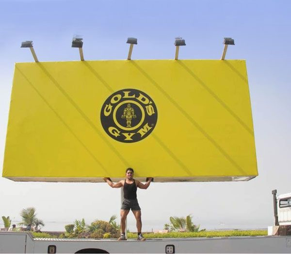 strong man holding up, lifting billboard - golds gym